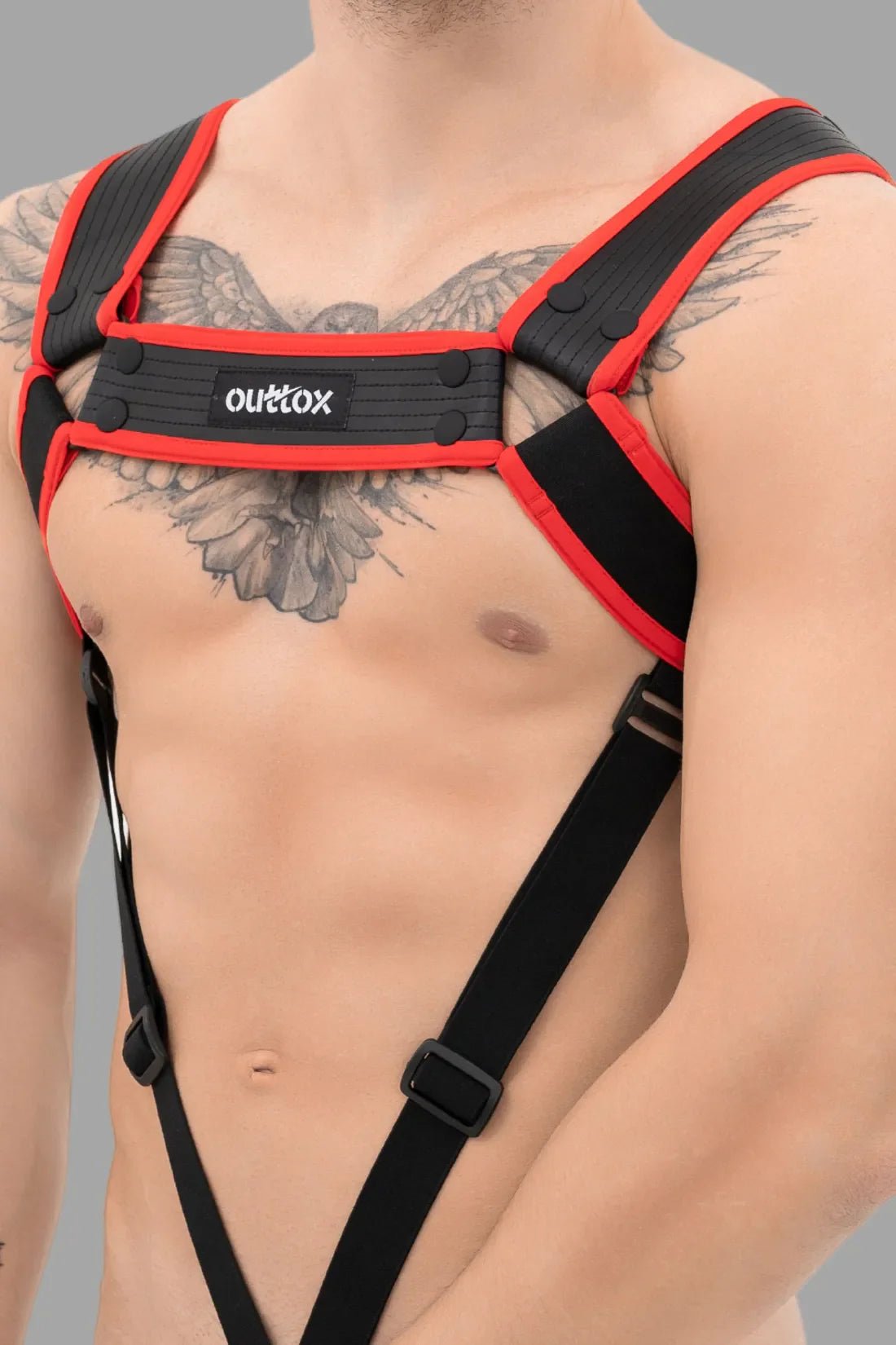 Outtox Body Harness with Snaps, Black and Red. Polyester, polyurethane, elastane blend. Adjustable, comfortable fit, integrated cockring. Costume accessory by Maskulo.