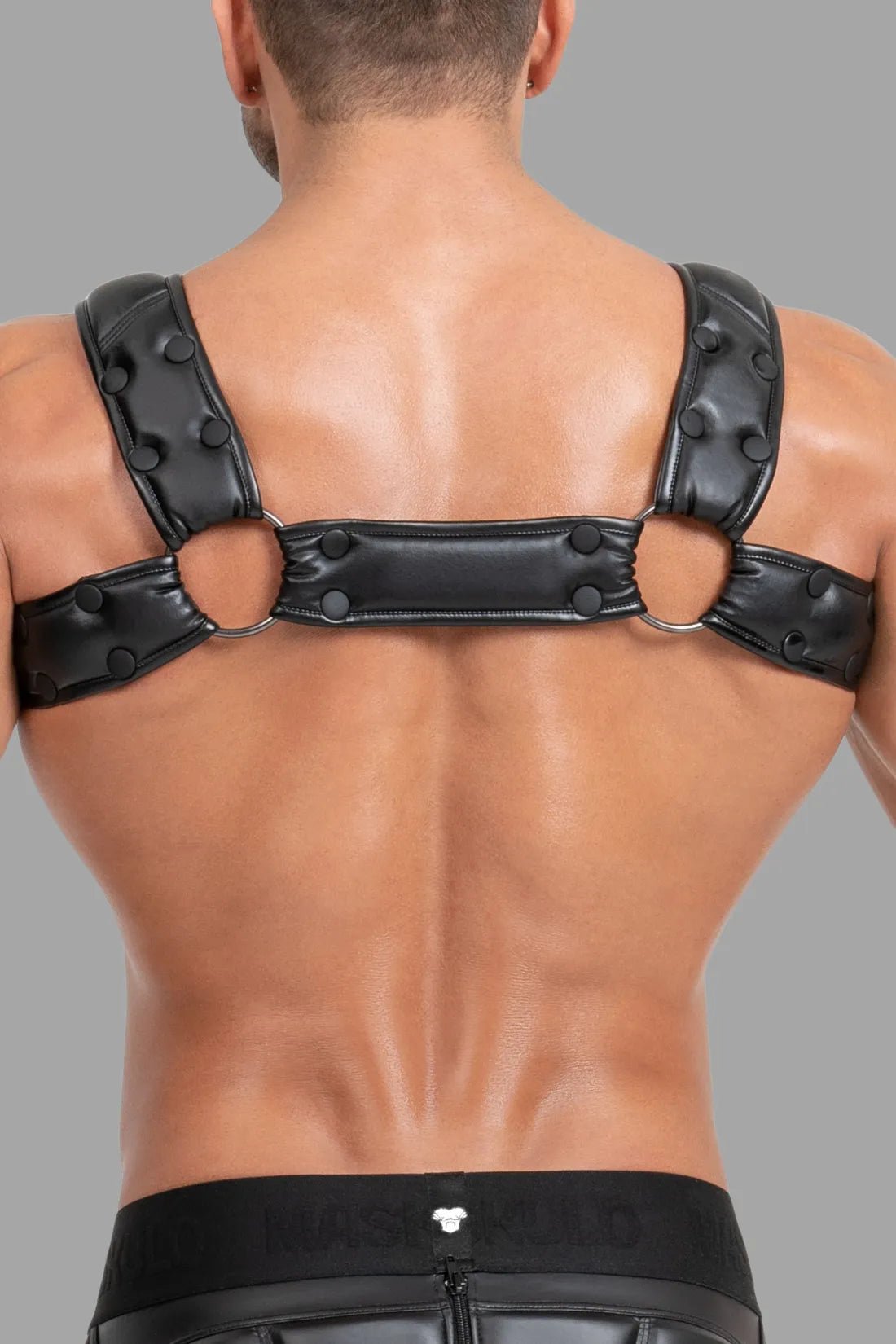 Maskulo Black and White Body Harness with Push-Up Effect. Features leather-look straps, white details, and stretch mesh back.